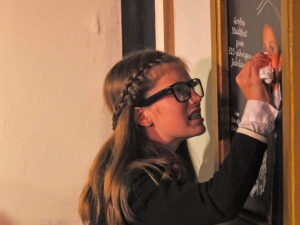 Fräulein Hofer versucht vergeblich die Schmiererei vom Plakat zu entfernen - © OVTP / gp