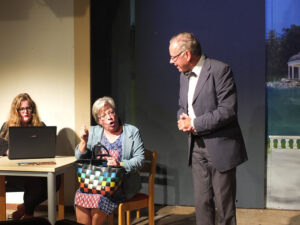 Ein Makler (R. Wagner) und seine Assistentin (J. Mach) überlegen, wie man das Alp-Traumhaus der Kundin (E. Mummert) an den Mann bringt. © OVTP / mib